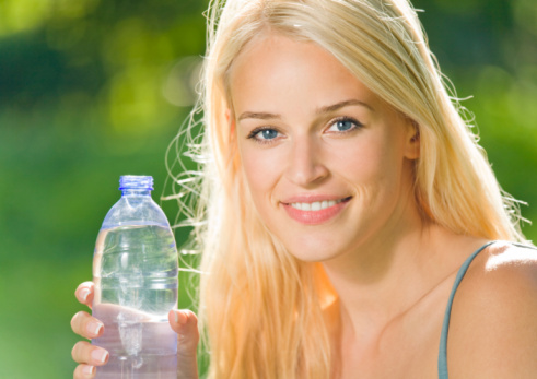 Portrait of beautiful smiling woman with bottle of water, outdoo